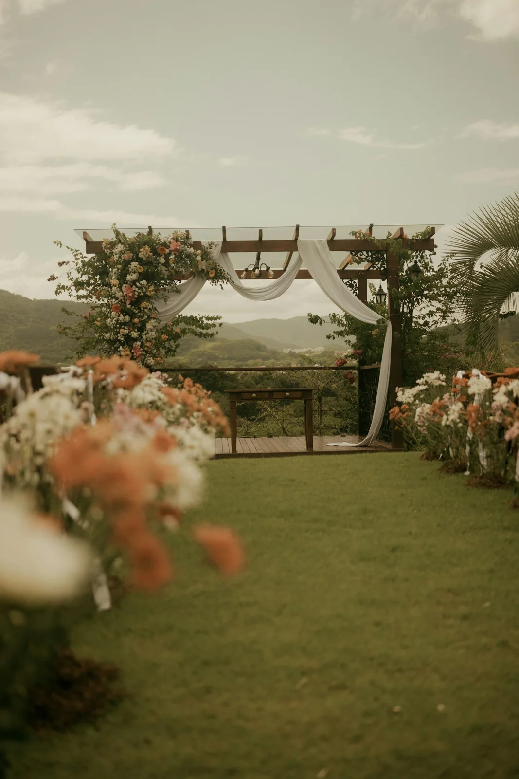 An outdoor wedding ceremony framed by flowing ivory drapes and flowers
